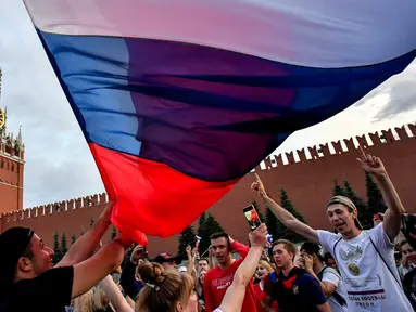 Suporter Rusia berpesta merayakan keberhasilan negaranya mengalahkan Spanyol pada laga 16 besar Piala Dunia di Moskow, Minggu (1/7/2018). Rusia untuk pertama kalinya lolos ke babak perempatfinal. (AFP/Yuri Kadobnov)