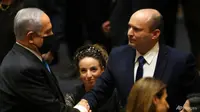 Perdana Menteri baru Israel Naftali Bennett berjabat tangan dengan Perdana Menteri Benjamin Netanyahu selama sesi Knesset di Yerusalem pada 13 Juni 2021. (Foto: AP/Ariel Schalit)