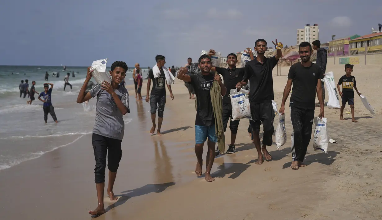 Warga Palestina berhamburan untuk mengumpulkan bantuan yang mendarat di Laut Mediterania setelah diterbangkan melalui udara di atas pusat kota Gaza, di pantai Zawaida, Jalur Gaza, Selasa, 29 Juli 2025. (AP Photo/Abdel Kareem Hana)