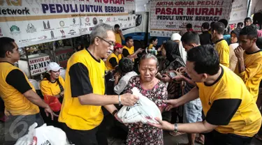 Senior Artha Graha Peduli Heka Hertanto (kiri) memberikan sembako pada Pasar Murah Ramadan 2016 di kawasan Pasar Benhil, Jakarta, Minggu (5/6/2016). Pasar Murah Ramadan 2016 ini diadakan oleh Artha Graha Peduli. (Liputan6.com/Faizal Fanani)