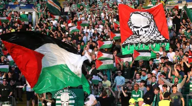 Para suporter Celtic mengibarkan bendera Palestina saat melawan Hapoel Beer Sheva asal Israel di pertandingan babak kualifikasi play off Liga Champions di Celtic park, (19/8).  Celtic menang atas Hapoel dengan skor 5-2. (REUTERS/Russell Cheyne)