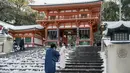 Seorang perempuan berpose di anak tangga Kuil Yasaka yang tertutup salju di Kyoto setelah salju tebal dan angin kencang semalaman mempengaruhi wilayah luas negara itu, Rabu (25/1/2023). Badan prakiraan cuaca memperingatkan akan ada salju tebal di beberapa wilayah dan gangguan lalu lintas akibat jalan membeku. (Photo by JIJI Press / AFP)