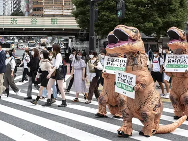 Aktivis kelompok hak hewan PETA mendesak orang untuk menjadi vegan selama protes di Tokyo, Jepang, Rabu (6/10/2021). Dalam aksinya, para aktivis mengenakan kostum dinosaurus. (CHARLY TRIBALLEAU/AFP)