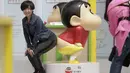 Seorang wanita berpose mengikuti gaya Crayon Shinchan saat berfoto di pameran Joy City, Beijing (5/5/2015). Lima puluh model karakter kartun Jepang dalam berbagai pose dan ekspresi dihadirkan dipameran tersebut. (REUTERS/Jason Lee)