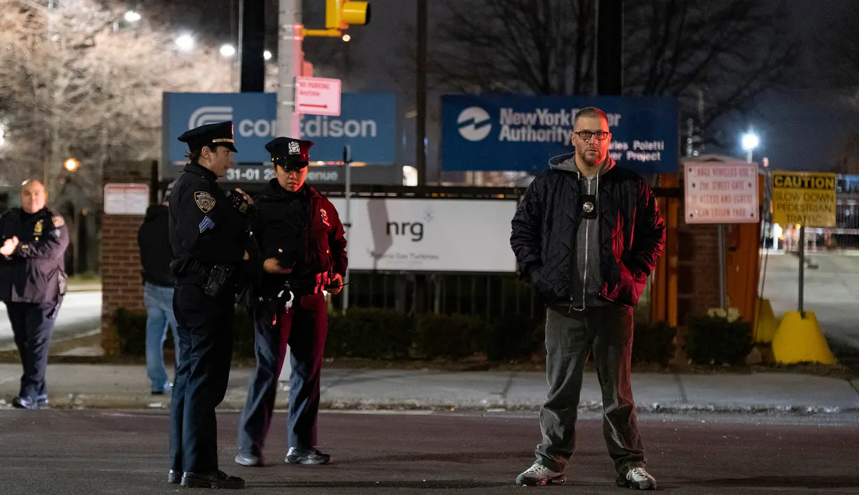 Petugas penegak hukum berjaga di depan perusahaan Con Edison setelah ledakan trafo listrik di distrik Queens, New York, Kamis (27/12). Ledakan itu menyebabkan cahaya biru menerangi langit New York dan membuat kegemparan di media sosial. (AP/Craig Ruttle)