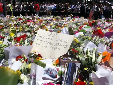 Sejumlah orang berdiri di balik pembatas tumpukan bunga di dekat Kafe Lindt, Sidney, Australia (16/12/2014). (REUTERS/David Gray)