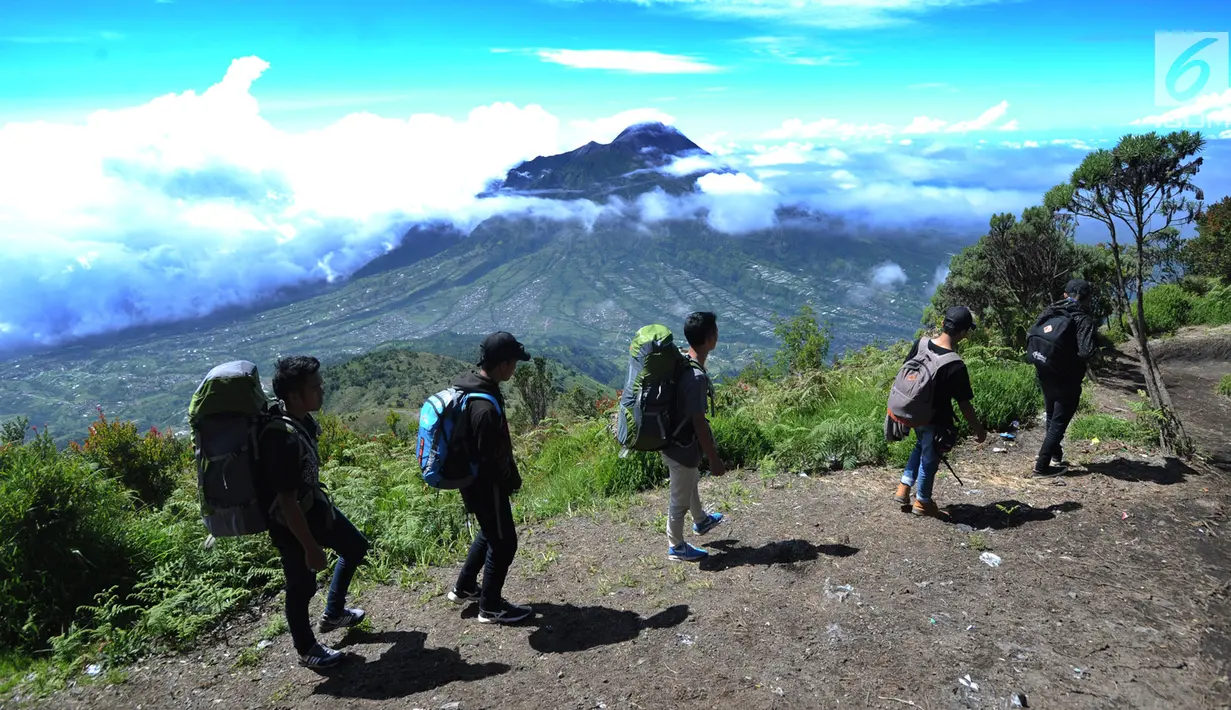 Para pendaki melintasi pemandangan Gunung Merapi dari atas Gunung Merbabu di Selo, Boyolali, Jawa Tengah, Sabtu (2/2/2019). Aktivitas Gunung Merapi dalam beberapa hari terakhir masih tinggi dan masih berada di level 2 atau waspada. (Merdeka/Arie Basuki)