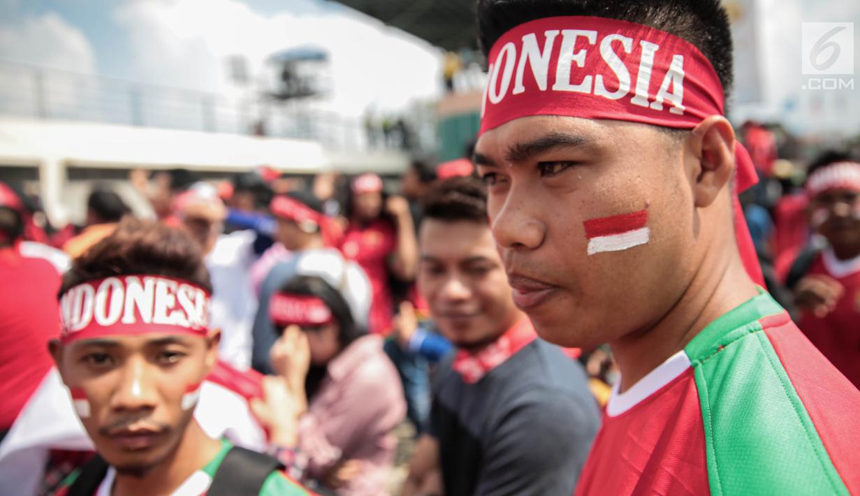 Suporter Garuda Muda mengecat pipinya dengan gambar bendera Merah Putih untuk mendukung Timnas Indonesia U-22 pada laga melawan Timor Leste, Minggu (20/8). Indonesia melakoni laga ketiga dalam lanjutan grup B SEA Games 2017. (Liputan6.com/Faizal Fanani)