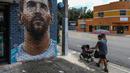 Pejalan kaki melintasi mural wajah Lionel Messi yang berada di salah satu jalan di Miami, Amerika Serikat. Messi memutuskan untuk bergabung dengan klub MLS, Inter Miami, pada Rabu (7/6/2023). (AFP/Giorgio Viera)