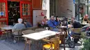 Orang-orang duduk di luar sebuah kafe di kota pantai Mediterania Israel di Tel Aviv, Rabu (27/5/2020). Setelah lebih dari dua bulan, Israel pertama kalinya mengizinkan restoran hingga kafe dibuka kembali usai pelonggaran pembatasan yang diberlakukan untuk mencegah Covid-19. (JACK GUEZ/AFP)