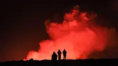 Sekelompok orang mengamati lelehan lava dan asap yang mengepul keluar dari sebuah celah saat terjadi letusan gunung berapi di dekat Grindavik, Islandia barat pada tanggal 8 Februari 2023. (Kristinn Magnusson/AFP/Islandia out)
