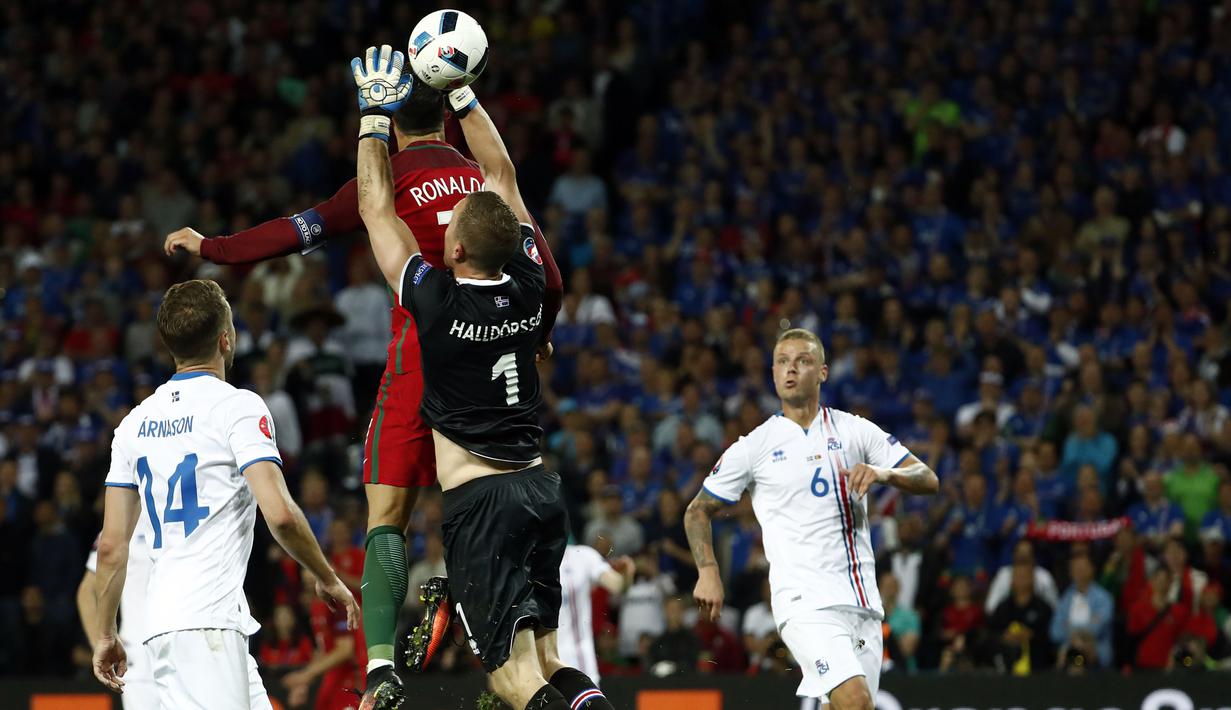 Kiper Islandia, Hannes Halldersson, menepis sundulan bintang Portugal, Cristiano Ronaldo, pada laga Grup F Piala Eropa di Stadion Geoffroy Guichard, St Etienne, Rabu (14/6/2016). Islandia bermain imbang 1-1 dengan Portugal. (AFP/Odd Andersen)