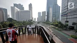 Warga berfoto saat arus lalu-lintas di Jalan Jenderal Sudirman, Jakarta, Senin (2/5/2022). Hiruk-pikuk kemacetan lalu-lintas di Ibu Kota berubah lengang saat sebagian besar warga mudik ke kampung halaman untuk merayakan Idul Fitri 1443 Hijriah. (merdeka.com/Iqbal S. Nugroho)