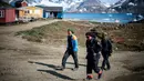 Warga berjalan di Desa Kulusuk, Kota Sermersooq, Greenland, Denmark, 16 Agustus 2019. Kawasan Greenland membeku sepanjang tahun termasuk di musim panas. (Jonathan NACKSTRAND/AFP)