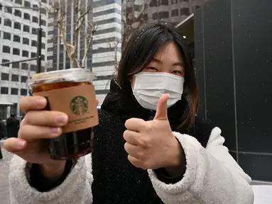 Foto yang diambil pada 26 Januari 2023 ini menunjukkan pekerja kantoran Jeong Jae-won berpose dengan es Americano selama wawancara dengan AFP di sebuah jalan di Seoul, Korea Selatan. Bahkan, kopi Americano ini kerap kali muncul dalam tayangan drama Korea atau menjadi kegemaran idol K-Pop. (Photo by Jung Yeon-je / AFP)