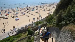 Orang-orang menuruni tangga menuju Pantai Bournemouth, Selatan Inggris pada Selasa 26 Mei 2026, saat kondisi gelombang panas menyebar ke sebagian wilayah tenggara Inggris dan London. (JUSTIN TALLIS/AFP)