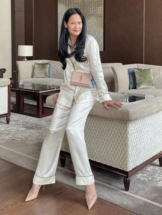 Perempuan kelahiran  21 Februari 1968 ini tampil dengan mode pakaia sleepwear dengan atasan long slevee dan bawahan warna putih, dipadukan heels dan slingbag warna senanda (@donnaharunofficial)