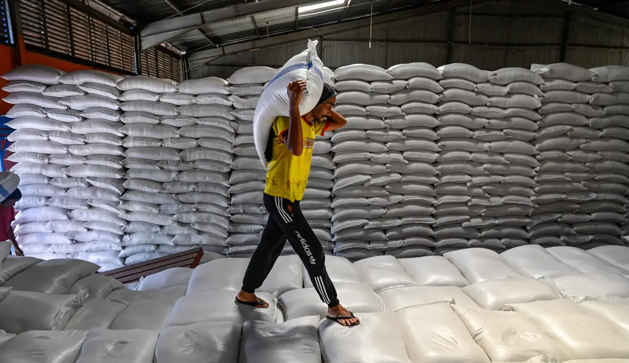 Sementara itu, stok beras di Sumatera Utara tercatat sebanyak 25 ribu ton dan di Sumatera Barat sekitar 9 ribu ton. Tampak dalam foto, seorang pekerja membawa sekarung beras di gudang Badan Urusan Logistik (Bulog) di Lambaro, Provinsi Aceh pada 29 Desember 2025. (CHAIDEER MAHYUDDIN/AFP)