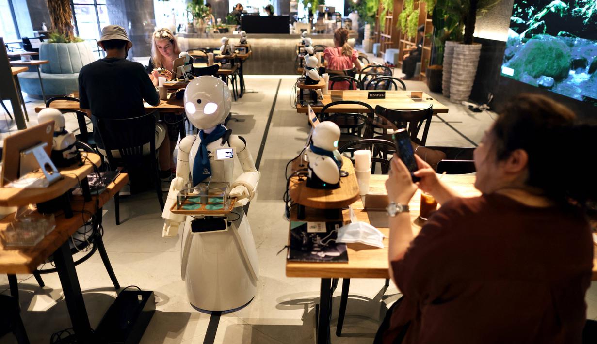 Robot humanoid mengantarkan minuman kepada pelanggan di Dawn Cafe, Tokyo, Jepang, 17 Agustus 2021. Peluncuran kafe ini bersamaan dengan Paralimpiade yang akan dibuka pada 24 Agustus. (Behrouz MEHRI/AFP)