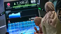 Orang-orang berdiri di samping layar yang menampilkan angka-angka perdagangan saham di gedung Bursa Efek Indonesia di Jakarta pada Rabu 10 September 2025. (BAY ISMOYO/AFP)