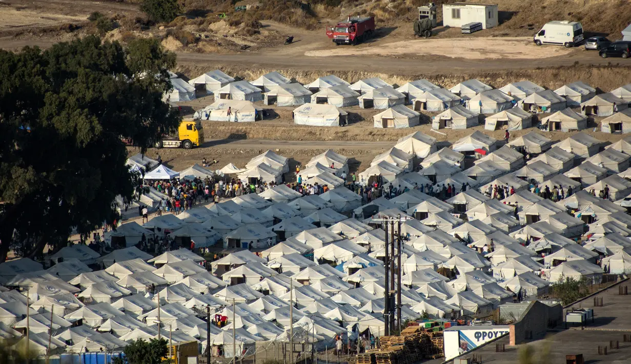 Migran berkumpul di kamp tenda sementara yang baru di Kara Tepe, Lesbos, Yunani, Kamis (17/9/2020). Lebih dari 5.000 pencari suaka yang kehilangan tempat tinggal setelah kebakaran kamp migran terbesar di Yunani, Kamp Moria, kini telah ditempatkan di fasilitas baru. (AP Photo/Panagiotis Balaskas)