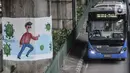 Bus transjakarta melintasi mural bertema protokol kesehatan Covid-19 yang menghiasi tiang pancang jalan tol di Jalan Ahmad Yani, Jakarta, Minggu (13/12/2020). (merdeka.com/Iqbal S. Nugroho)