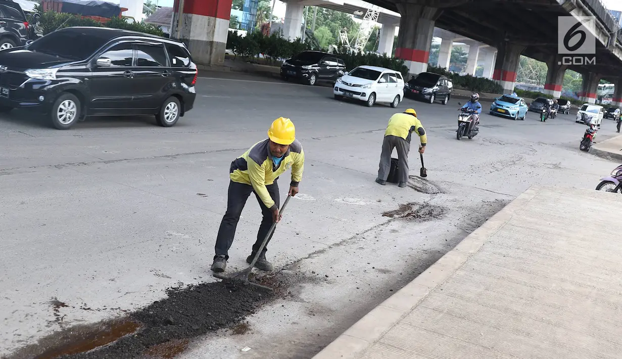 Petugas menambal lubang pada jalan yang rusak di kawasan Jatinegara, Jakarta, Kamis (7/2). Musim hujan yang mengguyur Jakarta selama beberapa waktu terakhir meninggalkan kerusakan pada sejumlah ruas jalan di Ibukota. (Liputan6.com/Immanuel Antonius)