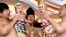 Dua pesumo menggendong bayi yang menangis selama Festival Nakizumo atau kontes bayi menangis di kuil Kamegaike-Hachiman, Jepang, Minggu (14/5). Lebih dari 100 bayi mengikuti kontes menangis yang diyakini bisa membuat bayi sehat. (Toru YAMANAKA/AFP)