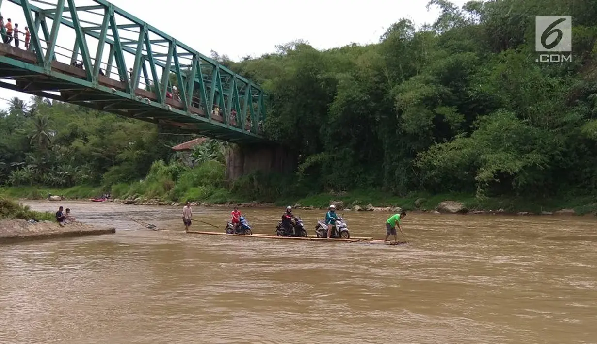 Sebuah rakit mengangkut motor dan warga menyeberangi Sungai Cisadane di Rumpin, Bogor, Selasa (13/3). Mereka terpaksa menaiki rakit akibat jembatan yang merupakan akses jalan utama Ciseeng -Rumpin masih dalam perbaikan. (Liputan6.com/Achmad Sudarno)
