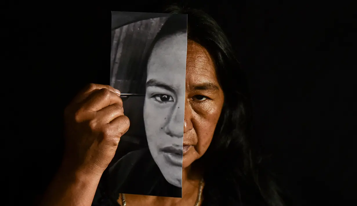 Lucila Huila, 53, ibu dua dari enam pria Kolombia yang dibantai oleh terduga anggota kelompok bersenjata pada 21 Agustus di El Tambo, berpose dengan foto putranya Heine Collazos, 25, di Popayan, Kolombia pada 28 Agustus 2020. Pembunuhan kembali berdarah di pedesaan Kolombia. (Luis ROBAYO/AFP)