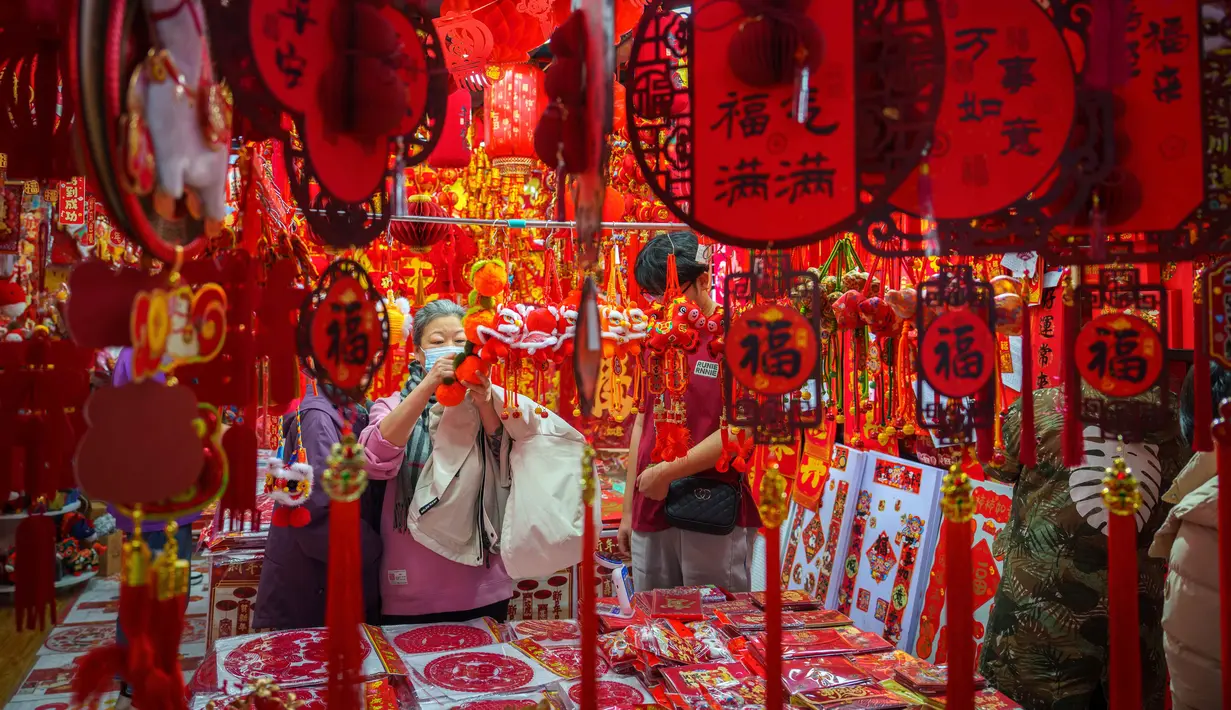 Bagi masyarakat China, Imlek memiliki makna sebagai simbol identitas dan jalinan ikatan keluarga yang kuat. Tampak dalam foto, para pembeli memeriksa dekorasi Tahun Baru Imlek di sebuah pasar di Beijing, China, Rabu 4 Februari 2026. (AP Photo/Vincent Thian)