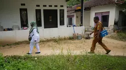 Tidak sendiri, Siti Nurjanah bersama rekan-rekannya rela menyusuri permukiman warga untuk memberikan vaksinasi campak kepada anak-anak yang telah terdaftar. (AP Photo/Dita Alangkara)