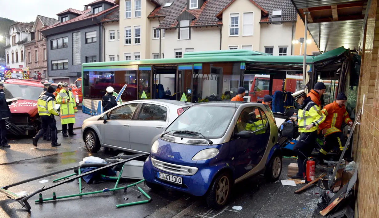 Petugas pemadam kebakaran berusaha mengevakuasi bus sekolah yang menabrak tembok sebuah toko di Eberbach dekat Mannheim, Jerman, Selasa (16/1). Polisi mulai melakukan penyelidikan untuk mencari tahu penyebab kecelakaan. (Rene Priebe/dpa via AP)