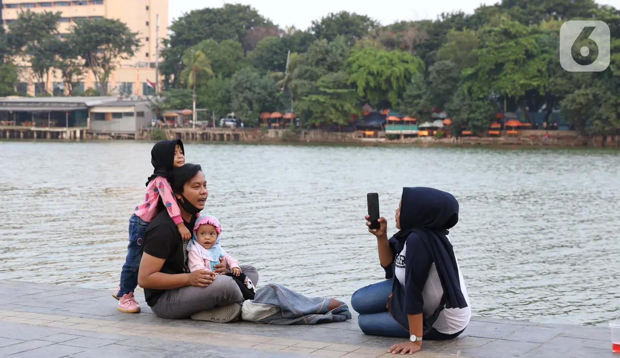 Warga berfoto di area pedestrian Danau Sunter, Jakarta, Sabtu (27/6/2020). Beragam aktivitas dilakukan warga sambil menikmati waktu sore di area Danau Sunter, Jakarta. (Liputan6.com/Helmi Fithriansyah)