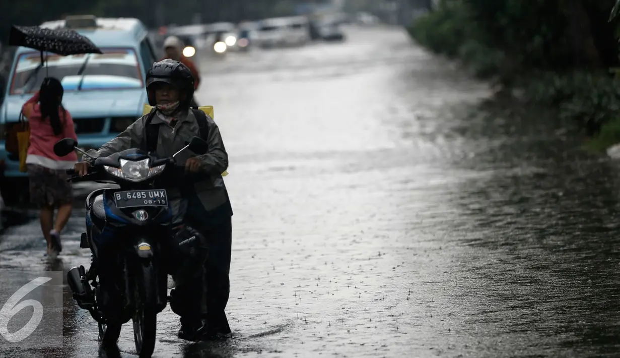 Warga saat mendorong motornya yang mogok akibat genangan air dikawasan Kelapa Gading, Jakarta, Jumat (26/2/2016). Hujan deras yang mengguyur Ibukota membuat beberapa ruas jalanan tersendat. (Liputan6.com/Faizal Fanani)
