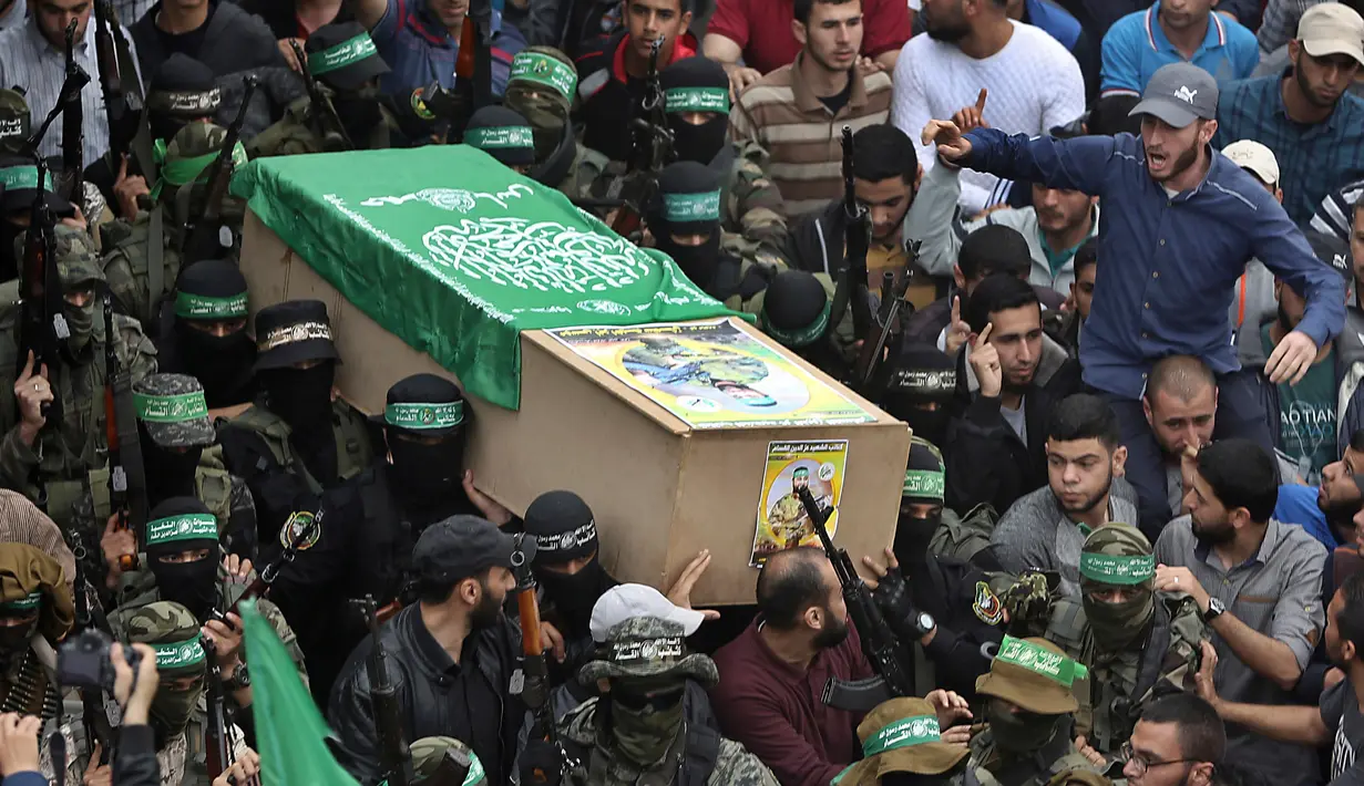 Tentara Hamas mengenakan topeng dan membawa senjata mengiringi peti jenazah enam pejuang mereka yang tewas di Deir el-Balah, Jalur Gaza (6/5). Sebelumnya telah terjadi ledakan yang menewaskan enam pejuang Hamas pada Sabtu (5/5). (AP/Khalil Hamra)