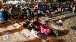 Sejumlah beristirahat usai menyaksikan atraksi kembang api pergantian tahun di Pantai Lagoon , Ancol, Jakarta, Minggu (1/1). Warga dari berbagai daerah sekitar Jakarta memilih menghabiskan malam tahun baru di kawasan Ancol.  (Liputan6.com/Gempur M. Surya)