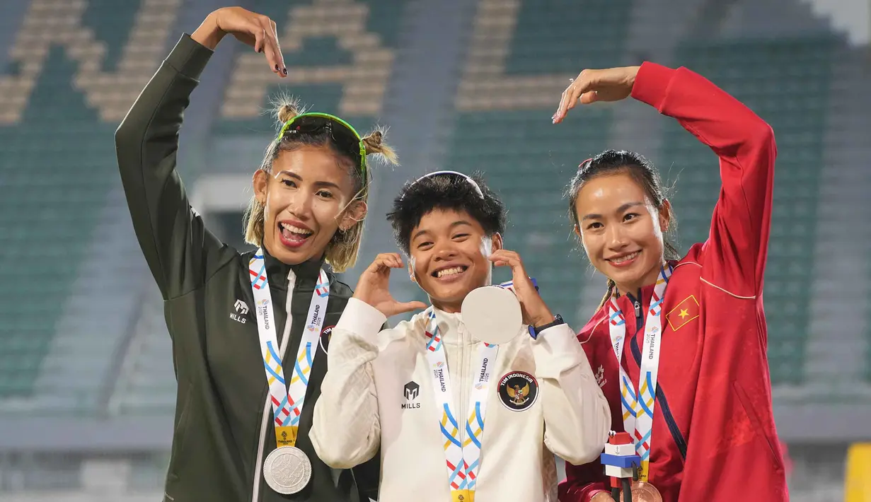 Dina Aulia menjadi yang tercepat dengan 13,21 detik, disusul Emilia Nova (13,27 detik) dan pelari Vietnam, Huynh Thi My Tien, yang membukukan waktu 13,43 detik. Tampak dalam foto, atlet lari gawang putri Indonesia, Emilia Nova (kir) dan Dina Aulia merayakan kemenangan bersama Thi My Tien Huynh (kanan) dari Vietnam saat upacara pemberian medali untuk final lari gawang 100 meter putri di SEA Games ke-33 di Bangkok, Thailand, Jumat 12 Desember 2025. (AP Photo/Achmad Ibrahim)