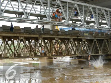 Anak-anak Ciliwung tampak riang saat melompat ke aliran sungai Ciliwung dari atas jembatan Kalibata, Jakarta, Jumat (13/11). Meningginya air sungai Ciliwung dimanfaatkan anak-anak Ciliwung untuk berenang dan bermain air. (Liputan6.com/Yoppy Renato)