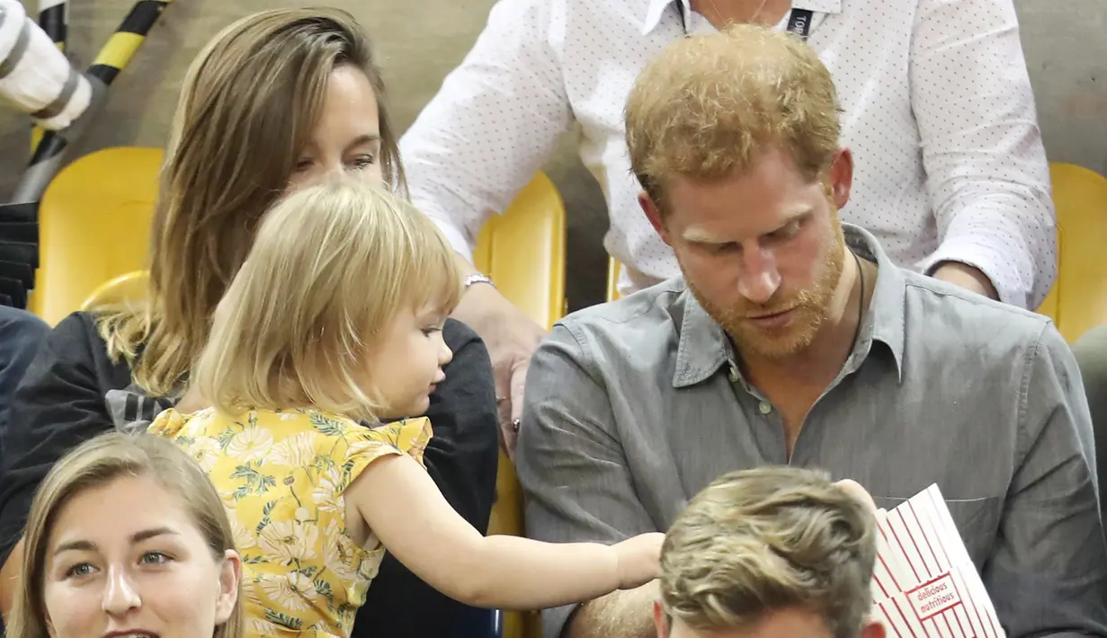 Seorang bocah bernama Emily Henson mencoba mengambil lagi popcorn Pangeran Harry dalam acara Invictus Games 2017 di Toronto, Kanada, Rabu (27/9). Harry pun mengizinkan Emily untuk berbagi popcorn dan menyuapinya. (CHRIS JACKSON/GETTY IMAGES/AFP) 