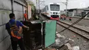 Kereta bandara melintas di dekat petugas yang sedang melakukan penertiban lapak dan bangunan liar di sepanjang jalur kereta di kawasan Grogol, Jakarta Barat, Kamis (22/2). (Liputan6.com/Arya Manggala)