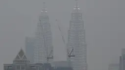 Menara Kembar Petronas diselimuti kabut asap di Kuala Lumpur, Malaysia (10/9/2019). Departemen Pendidikan Kota Sarawak, Malaysia meminta sekolah-sekolah ditutup sementara menyusul memburuknya udara akibat kabut asap kebakaran hutan di wilayah itu. (AFP Photo/Mohd Rasfan)