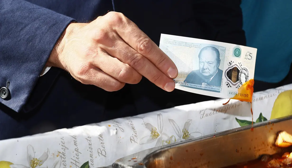 Gubernur Bank Inggris, Carney menunjukkan uang yang telah dicelupkan ke dalam kuah makanan, London, Selasa (13/9). Uang tersebut dikabarkan lebih tahan lama karena dicetak dengan menggunakan plastik film berbahan polimer. (REUTERS / Stefan Wermuth)