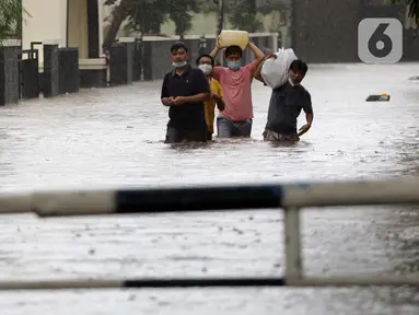 Warga berjalan menyusuri banjir yang menggenangi kawasan Jalan Wolter Monginsidi Jakarta dan sekitarnya, Sabtu (20/2/2021). Hujan yang mengguyur Jakarta sejak Jumat (19/2) membuat sejumlah titik di Jakarta terendam banjir. (Liputan6.com/Helmi Fithriansyah)