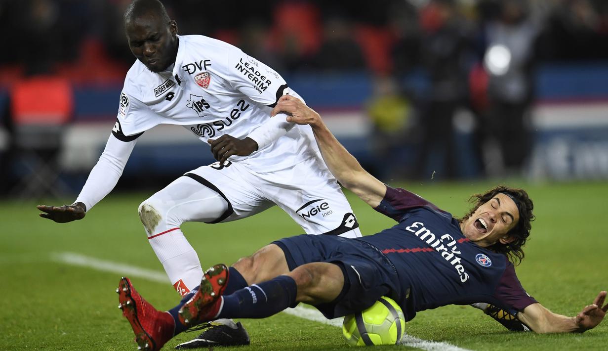 Pemain PSG, Edinson Cavani jatuh saat berebut bola dengan pemain Dijon, Cedric Yambere pada laga Ligue 1 di Parc des Princes stadium, Paris, (17/1/2018). PSG menang telak 8-0. (AFP/Christophe Simon)