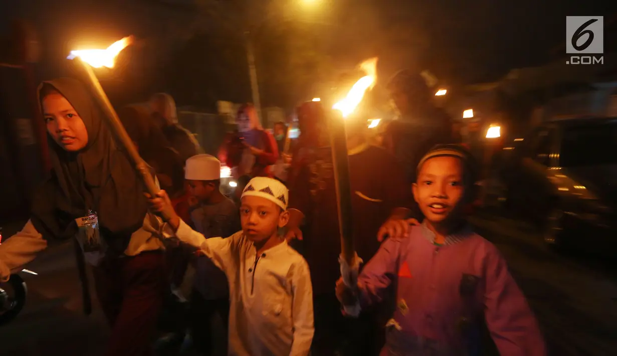 Sejumlah anak berpawai sambil membawa obor di Jalan Tengah, Batu Ampar, Jakarta Timur, Sabtu (24/6). Kegiatan tersebut dalam rangka menyambut Idul Fitri 1 Syawal 1438 Hijriyah. (Liputan6.com/Angga Yuniar)