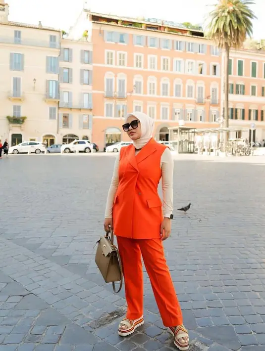Kombinasi blazer tanpa lengan berwarna oranye dengan celana panjang warna senada dan inner warna krem seperti Aurel Hermansyah ini juga tak kalah menarik. Untuk hijab, pilihlah warna cerah seperti peach. (Instagram/aurelie.hermansyah).