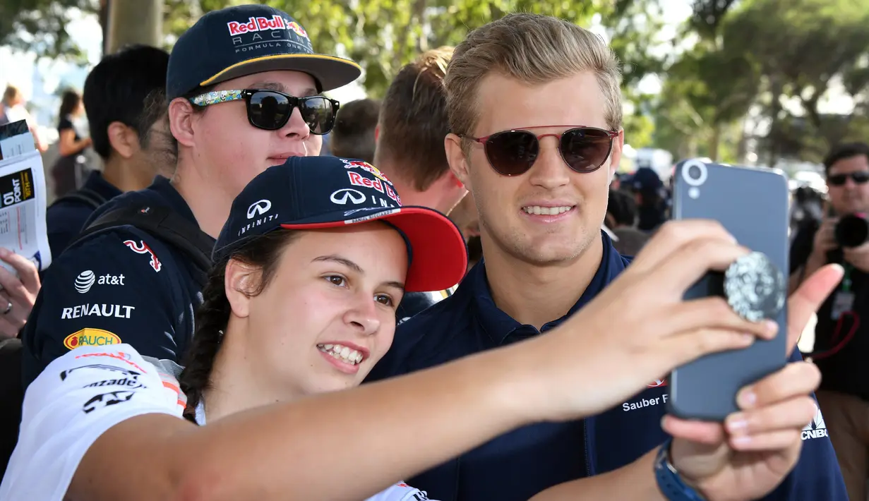 Pembalap Tim Sauber asal Swedia, Marcus Ericsson melakukan selfie dengan seorang penggemar menjelang sesi latihan bebas pertama di Grand Prix Australia, Melbourne, Jumat (24/3). (AFP Photo/WILLIAM WEST)