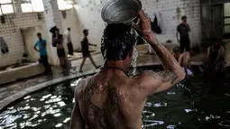 Pengunjung mengguyur kepala dengan air hangat dari belerang di Hamam Alli, Mosul, Irak, (27/4). Hammam Al Alil, yang berarti kamar Mandi Bagi Yang Sakit dalam bahasa Arab, kini opuler di kalangan pengungsi dan pasukan Irak. (AP Photo/Bram Janssen)