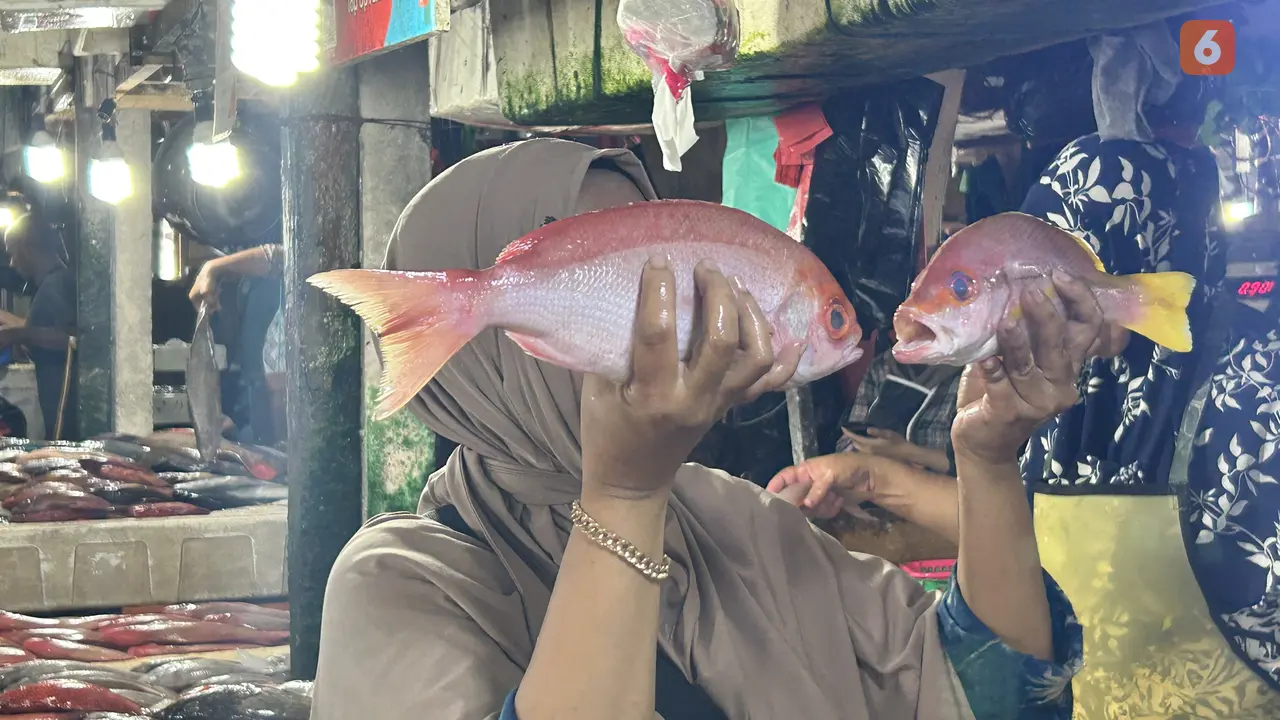 Seorang Pedagang Ikan di Pasar Kedonganan Tunjukkan Ukuran Ikan Siap Konsums